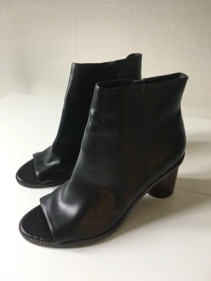 Svarta klackar  - Svarta klackar i läderimitation. Öppen tå & brun klack.  Nyskick, använda någon enstaka gång. 