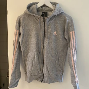 Tjocktröja från Adidas - En grå adidas-tröja med rosa ränder. Använd men fint skick. Storlek XS men passar S.