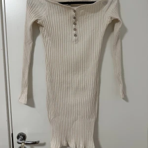 Ribbad klänning - Långärmad ribbad klänning som är lite off shoulder. Knapparna går att knäpp upp!
