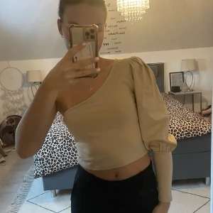 Topp från NA-KD - Beige topp med en volangärm från na-kf som aldrig är använd. 