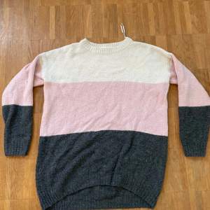 Stickad tröja med långa ärmar. Färgen är vit/grå/rosa