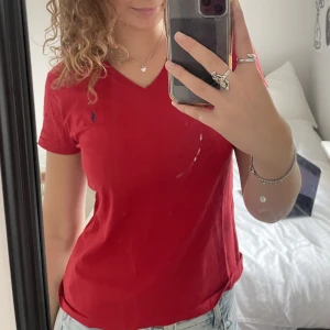 Röd Ralph lauren t-shirt - Supergullig röd Ralph lauren t-short med v-ringning. Skulle säga att T-shirten mer är en S än en M.