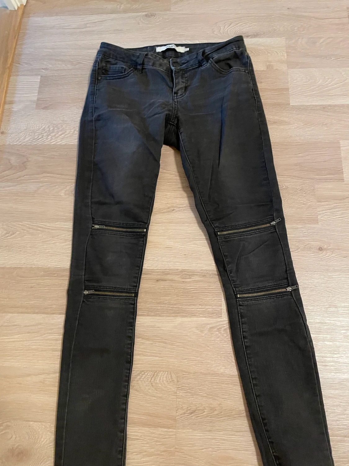 Grå jeans med dragkedja på knän