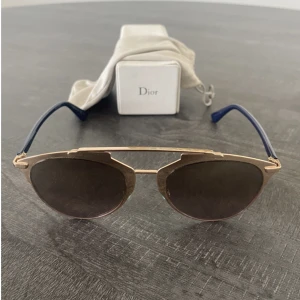 Dior solglasögon  -  Christian Dior 'Reflected' solglasögon med guldmetallram och mörkblå skalmar. Guld speglade rosa linser. Har använts få gånger och säljs då det inte kommer till en användning. Inköpta på NK i Göteborg för cirka 4000kr 