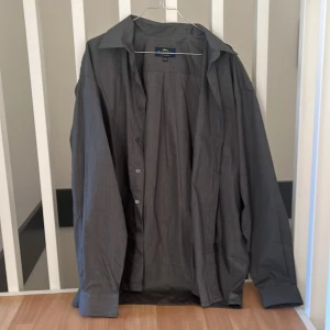 Mörkgrå skjorta - En mörkgrå skjorta lite mot det påsigare hållet. Ren men den tråden syns lite. Inget fel på knappen tho