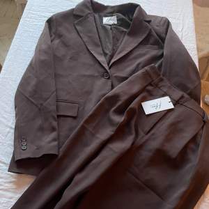 Set med blazer och kostymbyxor från NAKD, Hoss kollektion. Fin mörkbrun färg🤎strl 38 i blazern och 36 i byxorna. Det är i superskick, aldrig använt!