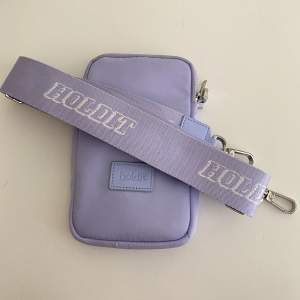 Holdit Pouch väska i färgen lavender Orginal pris 499kr Skick: fint skick, använd vid 1 tillfälle. 
