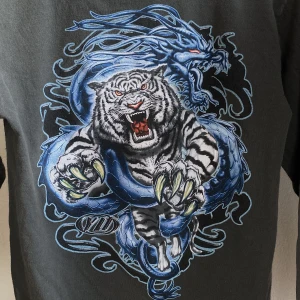 Alstyle Apparel Långärmad - Långärmad tröja med ett ed hardy liknande tigertryck med glitterdetaljer. Draktryck på bröstet och eldtryck på armen. Som helt ny, inga defekter! STRL Medium men skulle säga att den är lite mindre än en vanlig Medium.