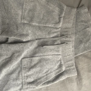 Juicy byxor grå - Säljer dessa gråa juicy byxor med fickor där bak i storlek ca då de inte längre används. Byxorna är väl använda och det finns tecken på användning men de var fortfarande i mycket fint skick. Metallen på snörena har länsat men i övrigt är de nästan som nya