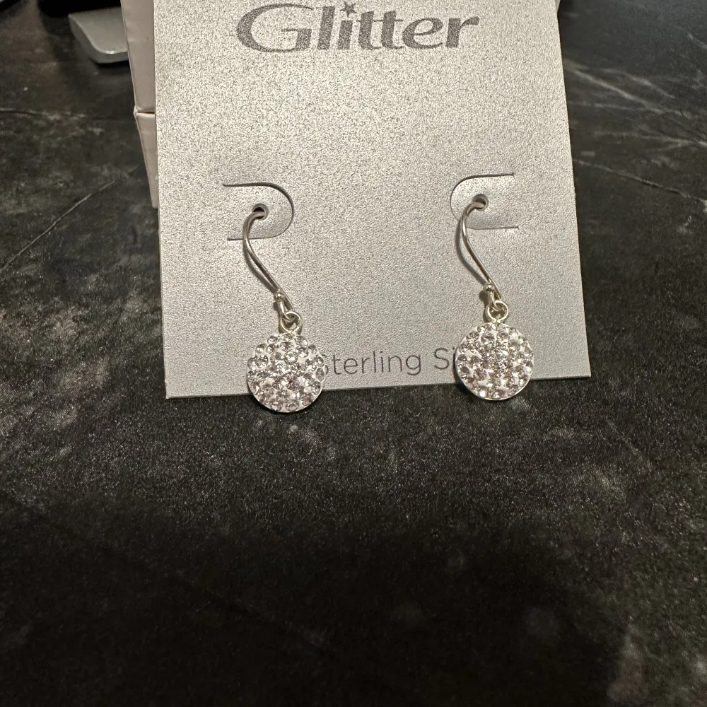 Oanvända hngande silver örhängen från glitter. Säljes pga fått present utan kvitto.. Accessoarer.