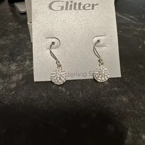 Oanvända hngande silver örhängen från glitter. Säljes pga fått present utan kvitto.