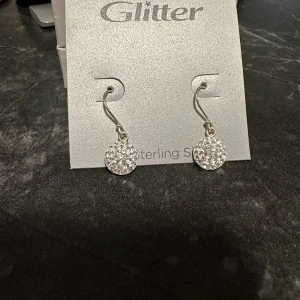 Silver örhängen - Oanvända hngande silver örhängen från glitter. Säljes pga fått present utan kvitto.