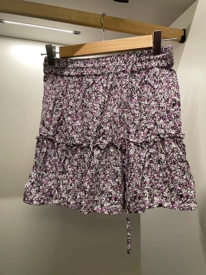 Somrig kjol! - Lila-blommig kjol från Zara med volanger, resår i midjan och inbyggda shorts så man slipper oroa sig över att den blåser upp. Använd Max 2 gånger 🫶Nypris ligger på 300:-