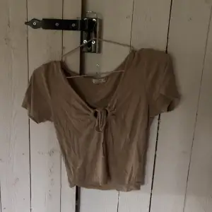Beige/brun T-shirt från cotton:om tror jag men köpt från sellpy, har en gullig knytning där fram mellan brösten 
