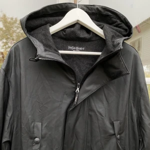 Yves Saint Laurent Regnjacka - Hej, säljer en snygg svart regnjacka från YSL. Polyester och ull blandning. 4 ytterfickor, 2 innerfickor. Fantastisk kvalite. Strl L & TTS. Bra skick, sparsamt använd. Väldigt bekväm, perfekt inför hösten. Nypris runt 15.000kr. Pris kan diskuteras. Hörs!