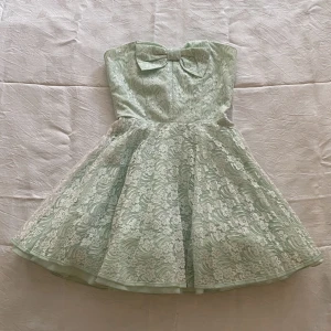Otrolig mini klänning med rosett - Så fin axelbandslös klänning i fin kvalitet, använd typ två gånger. Lite tyll under kjolen så att den blir vippig. Pastelligt mintfärgad/ljusblå 🦋 står UK 8 i men den är snarare XS, ca 58 cm i midjan.