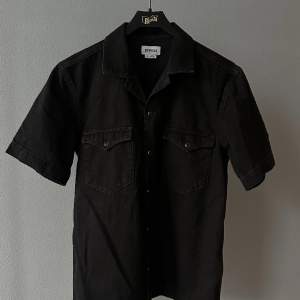 Kortärmad svart jeansskjorta från Weekday. Storlek XS, använd en gång.
