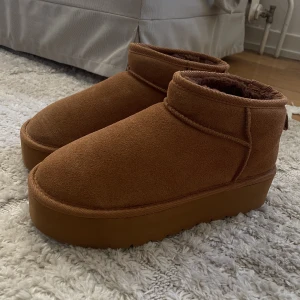 Ugg platform -  Säljer dessa skorna som är ugg kopior.Dom är aldrig använda men när jag testade dem råkade jag dra av flärpen på baksidan, därav är de sydda och kan inte returneras. Se sista bilden. Jag har storlek 37 men dom är stora i storleken därav säljer jag dom.