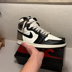 Air Jordan 1 High mocha. Skick 8/10 endast använda några gånger utan större defekter. Box o extra skosnören (vit och rosa) ingår. Skriv om ni har några frågor eller funderingar