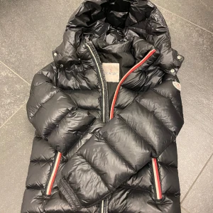 Moncler barnjacka Stl 152/12år - Jättefin Moncler jacka till barn Stl 152/12år. Använd en säsong. Liten reva på högerarmen, dock lagad.