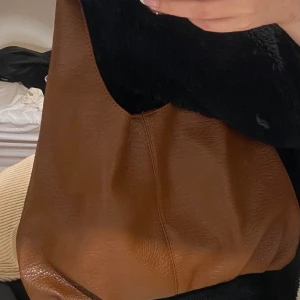 Brun mellanstor väska - Intressekoll på min bruna väska. Så söt och är i mellan storlek. Har en liten väska inuti som man kan stänga med dragkedja. Så fin väska och fint skick!