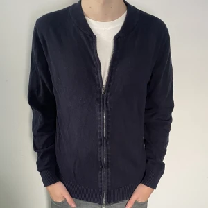 Marinblå cardigan - Sjukt snygg marinblå fullzip/cardigan från Grand Frank. Skick 8/10. Storlek M. Passar även S. Modellen är 180 cm. Nypris 999kr. Vårat pris 299kr. Skriv vid minsta fundering!📩