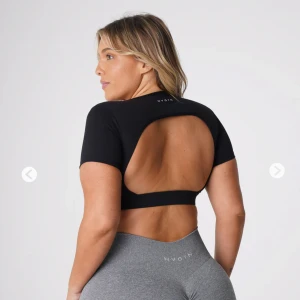 Svart träningstopp från NVGTN - Säljer denna snygga croppade t-shirt från nvgtn som är helt öppen i ryggen. Jättesnygg, men kommer inte till användning längre och det är därför jag säljer den. 