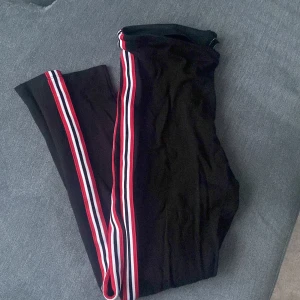 Tights - Svarta tights med svart/vit/röd remsa längst hela yttersidan av benet i Stl M