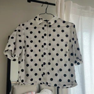 Kort prickig blus - Prickig blus i kort modell från Topshop Anmärkning: fläckig vid kragen och framtill (se bilder)