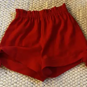 Röda tyg shorts med två rosetter på sidorna. 