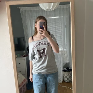 Grå t-shirt - En grå t-shirt med harvard motiv på, kragen är klippt och därför kan va off shoulder 💕