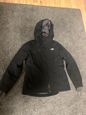 Skidjacka  - Skidjacka/vinterjacka från The North Face. Jackan är i bra skick och har både bra fickor (två vanliga fickor, bröstficka, liftkortsficka på vänstra armen) och snöskydd invändigt. Öppen för att diskutera prisförslag!!