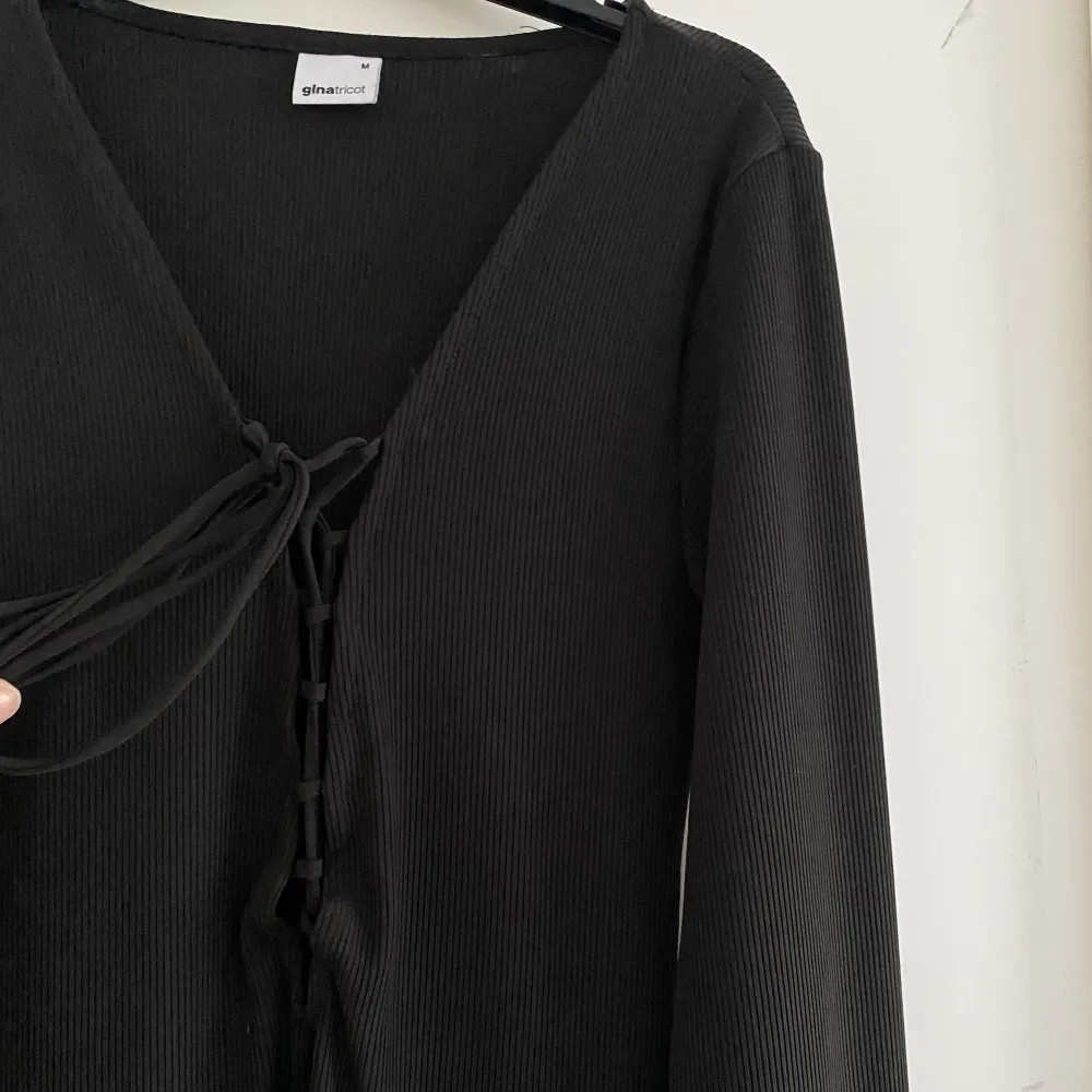 Säljer denna svarta ribbade klänningen från Gina Tricot i storlek M❣️ Har endast använts en gång och är i väldigt bra skick!! Den sitter fint mot kroppen och har en snörning där fram. Klänningar.