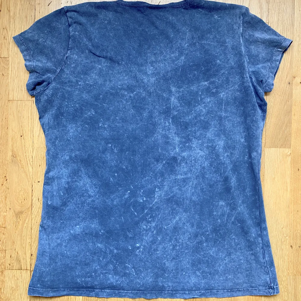 En extremt snygg ljusblå tröja med ännu snyggare detaljer! Ett tryck på framsidan likt Affliction och volangliknande axlar, samt fungerande knappar längs tröjans krage! Väldigt skönt material, perfekt för sommaren! Står storlek 4, sitter som en M. T-shirts.