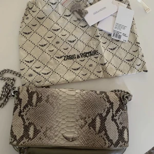 Zadig väska - Säljer nu min Zadig Limited Edition Rock Savage, pga lite användning av den. Väl använd men inget som påverkat skicket. Det ingår band, ett axelband, dustbag och äkthetensbevis. Nypris 3600kr! Har 3 fack :)
