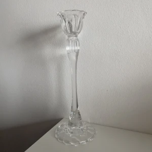 Ljusstake  - Charmig och elegant ljusstake i glas (H: 28cm, B: 11cm). 1 ljusstake 50kr, 2 ljusstakar 80kr, 3 ljusstakar 100kr, 4 ljusstakar 120kr (Fraktkostnaden varierar beroende på antal ljusstakar). 