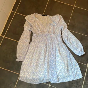 Blå klänning med vita blommor  - Blå, vit klänning i nyskick, Använd 1 gång.