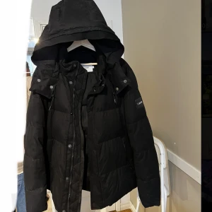Puffer jacket Calvin Klein   - Säljer en väldigt fin Calvin Klein jacka för herr som har används en gång i storlek XL köpt för 3000kr. Väldigt varm och skön jacka som passar till vintern har även en stor luva. Jackan är vattentät och är matt på utsidan vilket gör att regnet glider av. 