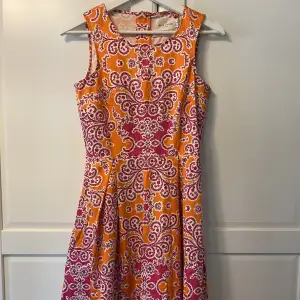 Orange blommig klänning insydd i midjan. Häftigt mönster. Använd endast en gång. Perfekt till sommaren/midsommar. Storlek 34.  