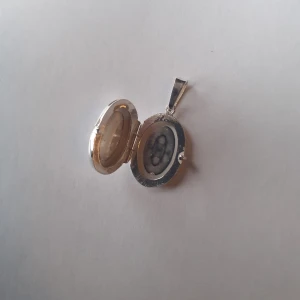 Silverberlock  - Berlock i äkta silver. Går att öppna och placera bilder eller något annat man vill bära med sig i. Har gravering på framsidan och slät baksida. Finns 2 st exemplar kvar och säljer dem för 150kr/st 