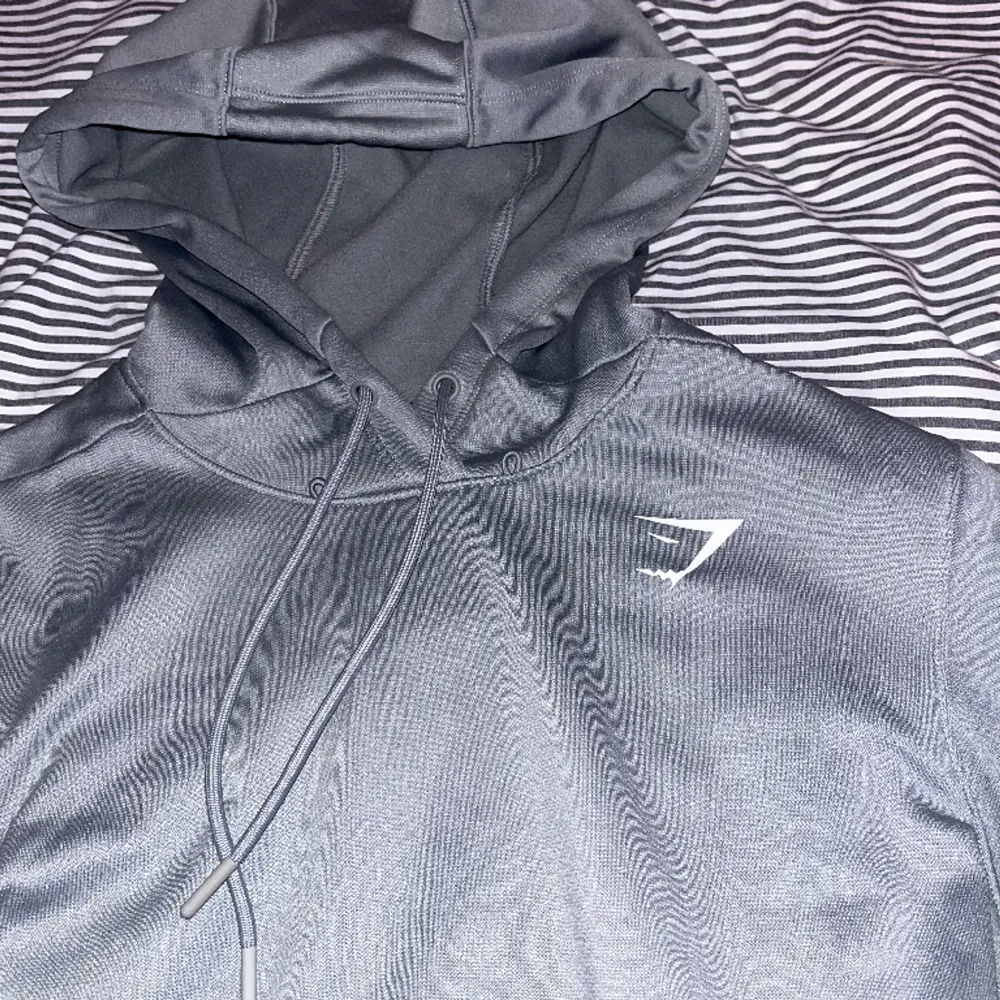 Riktigt skön gymshark hoodie i perfekt skick. Materialet är bekvämt och andas vilket gör att den är skön att bära. Modellen är lite mer avlång än andra vilket gör att du lättare kan utföra vissa rörelser. Säljes på grund av att den är blivit för liten.. Hoodies.