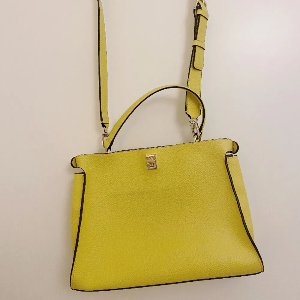 Smidig axel/handväska från Guess i en härlig gul färg. Två separata fack som man kan öppna var för sig. Har en missfärgning på baksidan (se bild) som ev går att tvätta bort. Väskor.