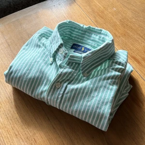 Ralph lauren - Grönvit randig oxford-skjorta - Stilren skjorta i vita och gröna ränder. I fint begagnat skick. Modellen är slim fit, står även ”Oxford stretch” på tag. Storlek är small.  Ca 80 cm längd över ryggen. Ca 50 cm från armhåla till ärmens slut.