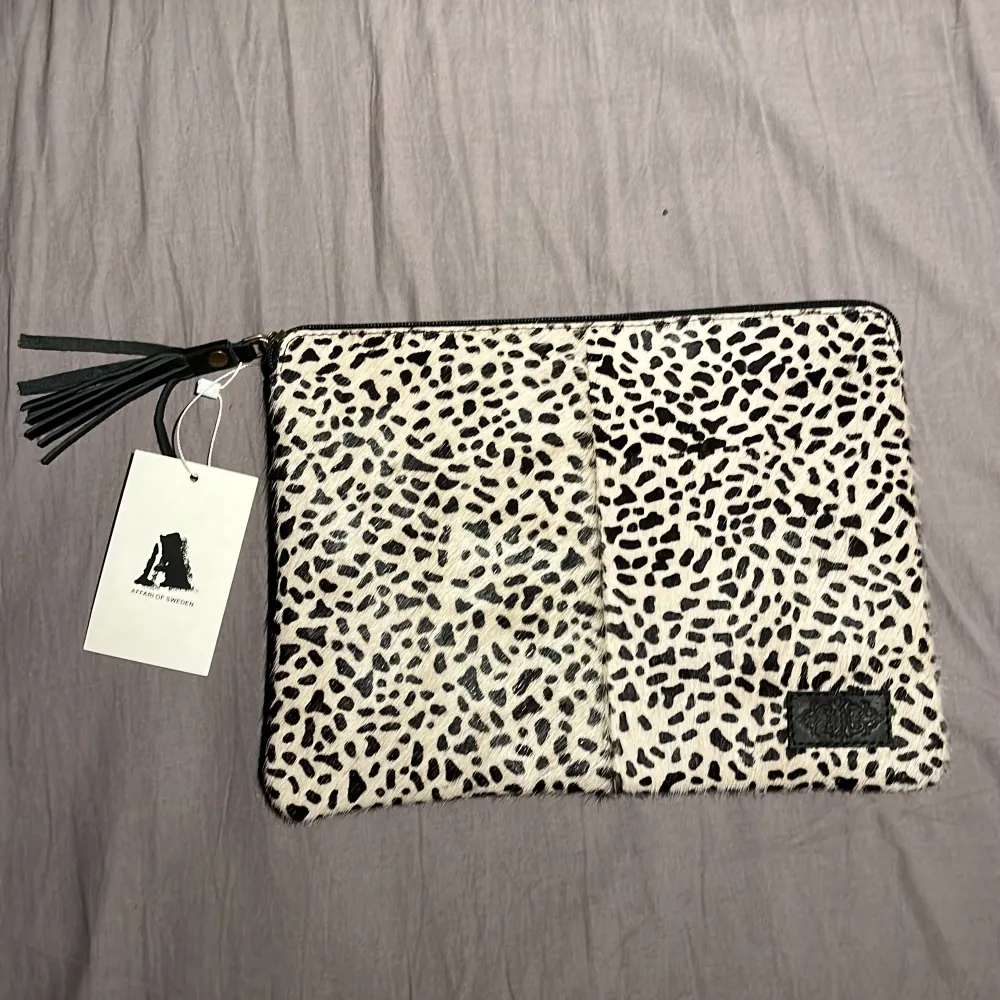 Här har vi en leopardmönstrad handväska ifrån Affari of sweden med svarta detaljer väskan är gjord i fake päls. På insidan av väskan hittar vi korthållare men även stort utrymme för andra föremål samt en ficka med dragkedja, ALDRIG ANVÄND. Väskor.