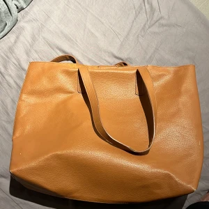 Handväska från ellos - En brun fake läder väska från Ellos väskan är stor och rymmlig men även i  gott skick, i väskan finns det mindrefack med dragkedja och väskan stängs med guldigt magnet knäppe