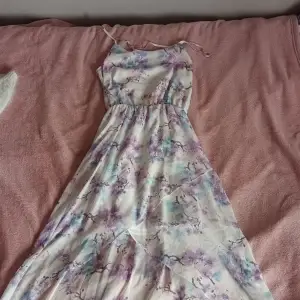 En klänning från cubus i strl 164 men som passar xs-s. Det är ljuslila och ljusblå blommor på som är lite längre bak än fram. den perfekt till skolavslutning tex