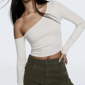 One shoulder tröja - Långärmad one shoulder tröja från Stardivarius i strl S. Aldrig använd endast prövad och säljer då den inte kommut till användning och för sent att skicka tillbaka. Färgen är Creme vit. Köptes för 179kr.  Nyskick med prislapp kvar 💕💕