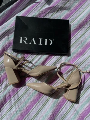 Lackade klackskor  - Beiga lackade klackskor ”Lianni” från Raid. Perfekta till en studentbal eller annan tillställning.  Använda en gång då jag testade gå i dem men min bal blev aldrig av så ovansidan av skorna är helt felfria, inga märken alls!  Nypris 429kr 
