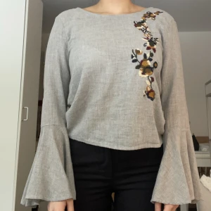 Blommig blus med öppen rygg - Blommig blus med volangärm i fint skick! Öppen rygg med knytning baktill. Tunn och luftig. Underbar sommar/vårblus!  87 % bomull, 13 % polyester.