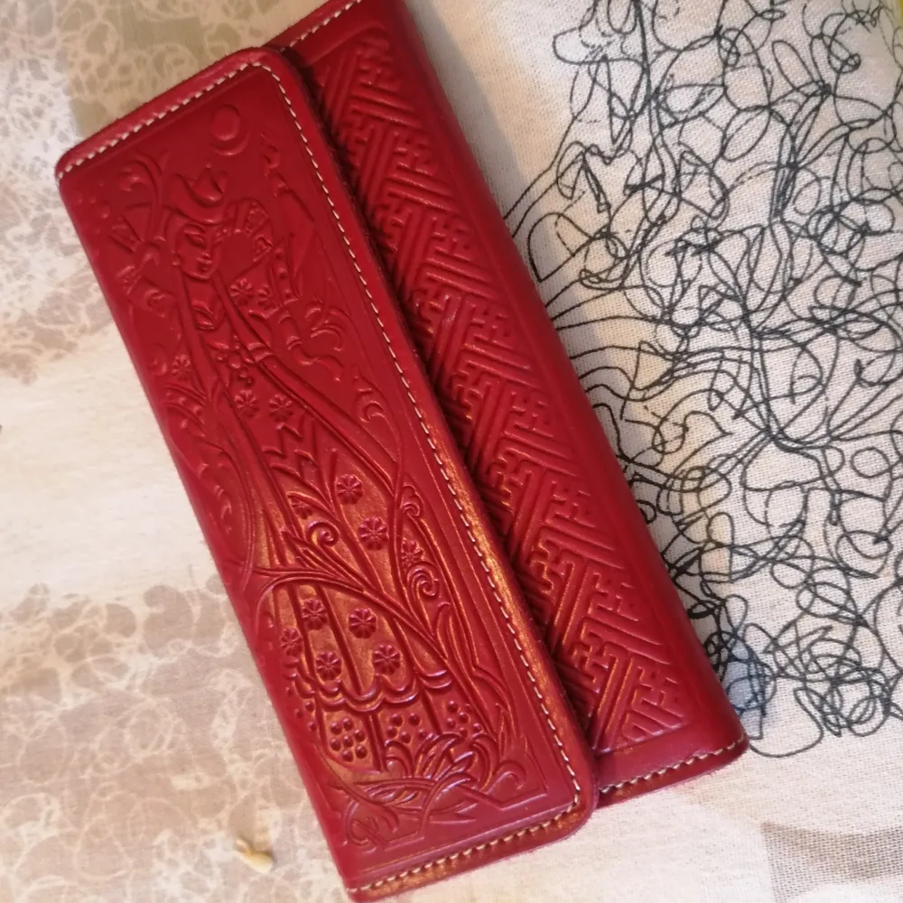 En vacker portmonnä / plånbok med vackra detaljer i skinn från Mongoliet. Har plats för kort, ett myntfack, två större fack för sedlar och ett fack där man kan lägga kvitton/lappar m.m. och ett genomskinligt fack för körkort/idkort. . Övrigt.